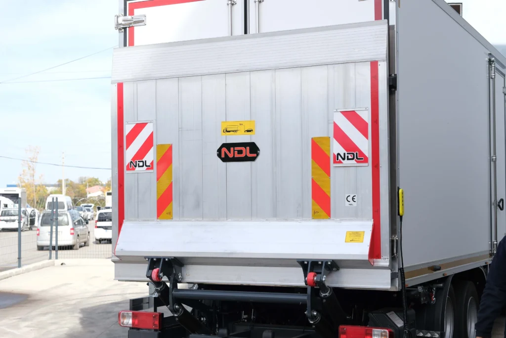 مؤخرة شاحنة تحتوي على باب معدني مع شعار NDL وعلامات تحذيرية ملونة.
